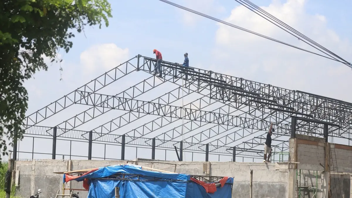 ESKTRA HATI-HATI: Tiga orang pekerja mengerjakan pemasangan atap proyek KDMP di Desa Ngabar, Kecamatan Jetis, Kabupaten Mojokerto, tanpa menggunakan alat pengaman, Jumat (17/4). Kondisi ini turut menjadi sorotan Komisi IV DPRD Kabupaten Mojokerto karena dinilai cukup membahayakan pekerja.  (Sofan JPRm)