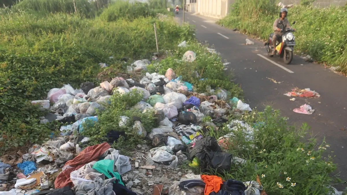 SAMPAH LIAR: Seorang pengendara sepeda motor melintasi kawasan Jalan Joko Tole, Kecamatan Magersari, Kota Mojokerto, Senin (4/5). Area tersebut masih dipenuhi sampah-sampah liar diduga hasil sampah rumah tangga. (Sofan JPRM)