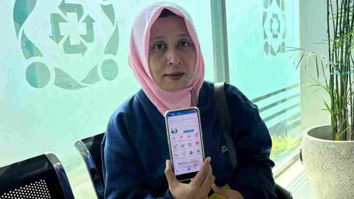 Seorang pengunjung kantor BPJS Kesehatan menunjukkan layanan aplikasi mobile. 