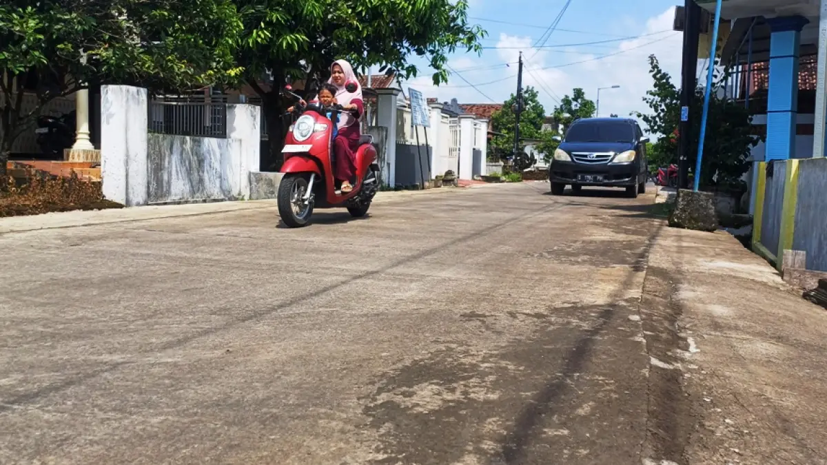INFRASTRUKTUR: Seorang warga memanfaatkan jalan lingkungan di Dusun Wonokerto, Desa Windurejo, Kecamatan Kutorejo, yang tuntas dibangun 2025 lalu. (Dodik JPRM)