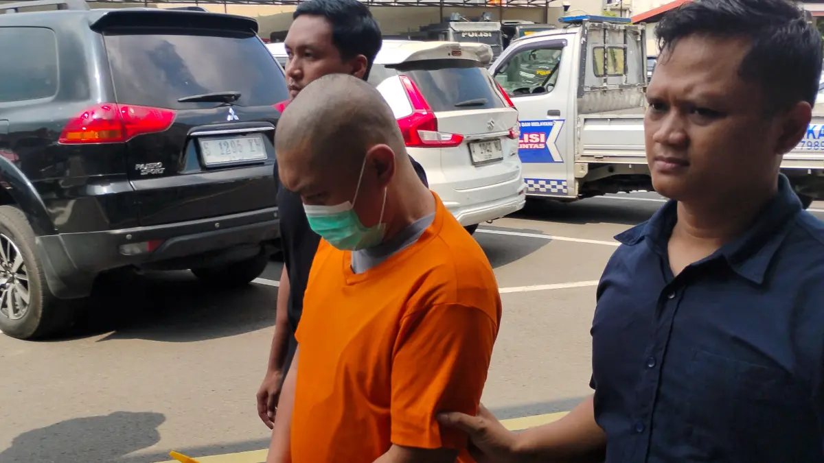 DITAHAN: IM (tengah) digelandang petugas ke sel tahanan Polres Mojokerto Kota pada Rabu (20/5). (Martda JPRM)