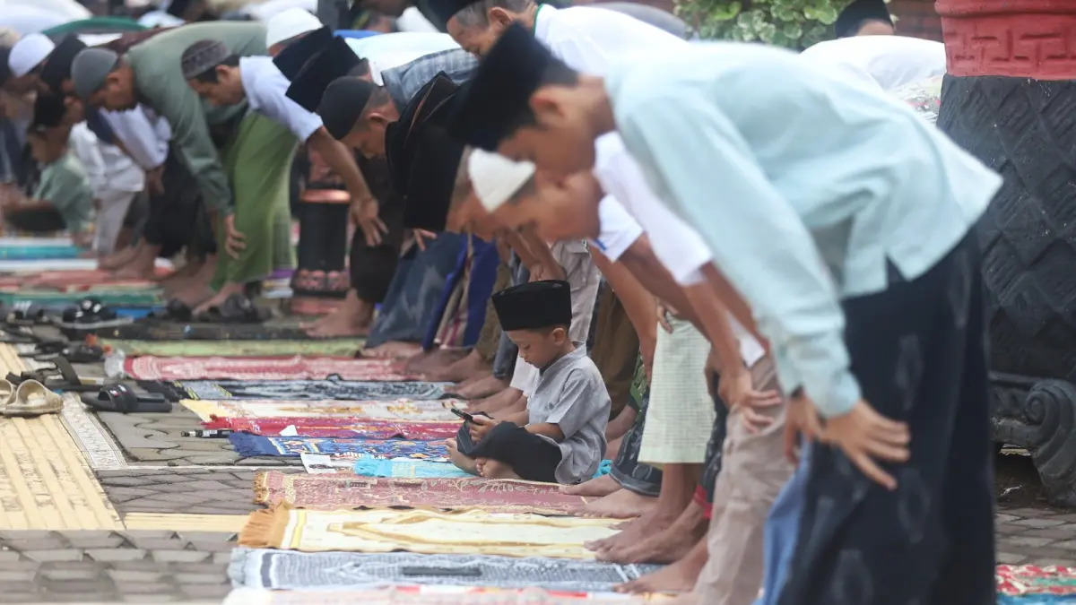 IBADAH IDULADHA: Umat Muslim mengikuti ibadah salat Iduladha di Masjid Agung Al-Fattah, Kota Mojokerto, Rabu (27/5). Tampak seorang anak memainkan ponsel sembari menunggu rampungnya salat. (Sofan JPRM)