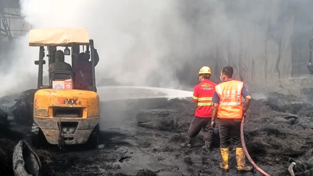 MASIH BERASAP: Petugas damkar melakukan pembasahan dan mengurai material ban yang masih terbakar, kemarin (29/5) sore. (Martda JPRM)