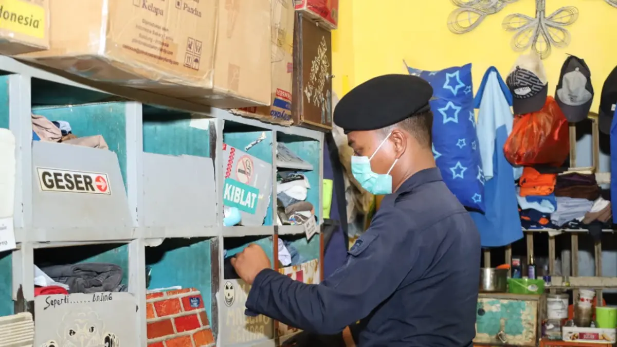 DIGELEDAH: Petugas gabungan memeriksa kamar hunian warga binaan Lapas Kelas IIB Mojokerto dalam razia yang digelar Senin (1/6) malam. (Adi JPRM)