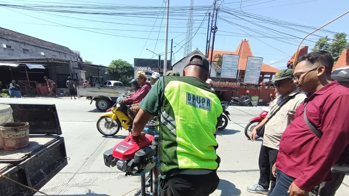 CEK KESESUAIAN: Petugas Dinas PUPR Kabupaten Mojokerto melakukan core drill untuk mengambil sampel beton untuk pengujian ketebalan dan kualitas jalan di simpang empat Lebaksono, Kecamatan Pungging, kemarin (5/6). (Rizal JPRM)