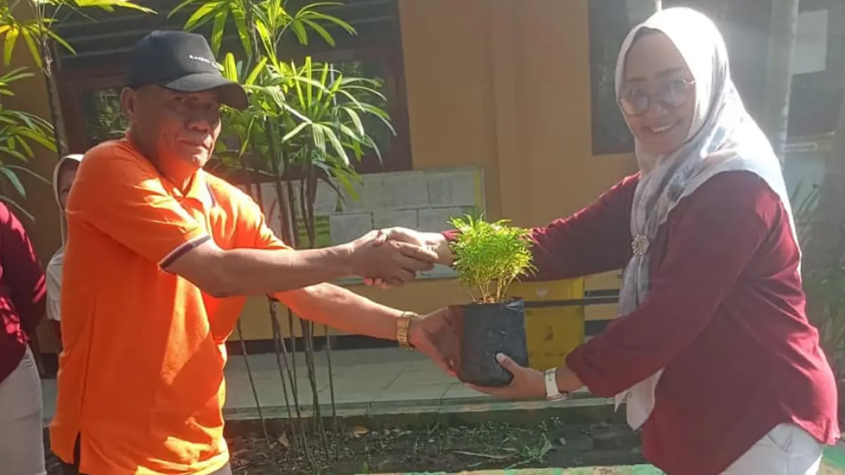Kepala SDN Mojotamping Ika Yuni Mahardika Rini, S.Pd, menerima bantuan bibit tanaman dari Kades Mojotamping H. Akhmad Sumanan.