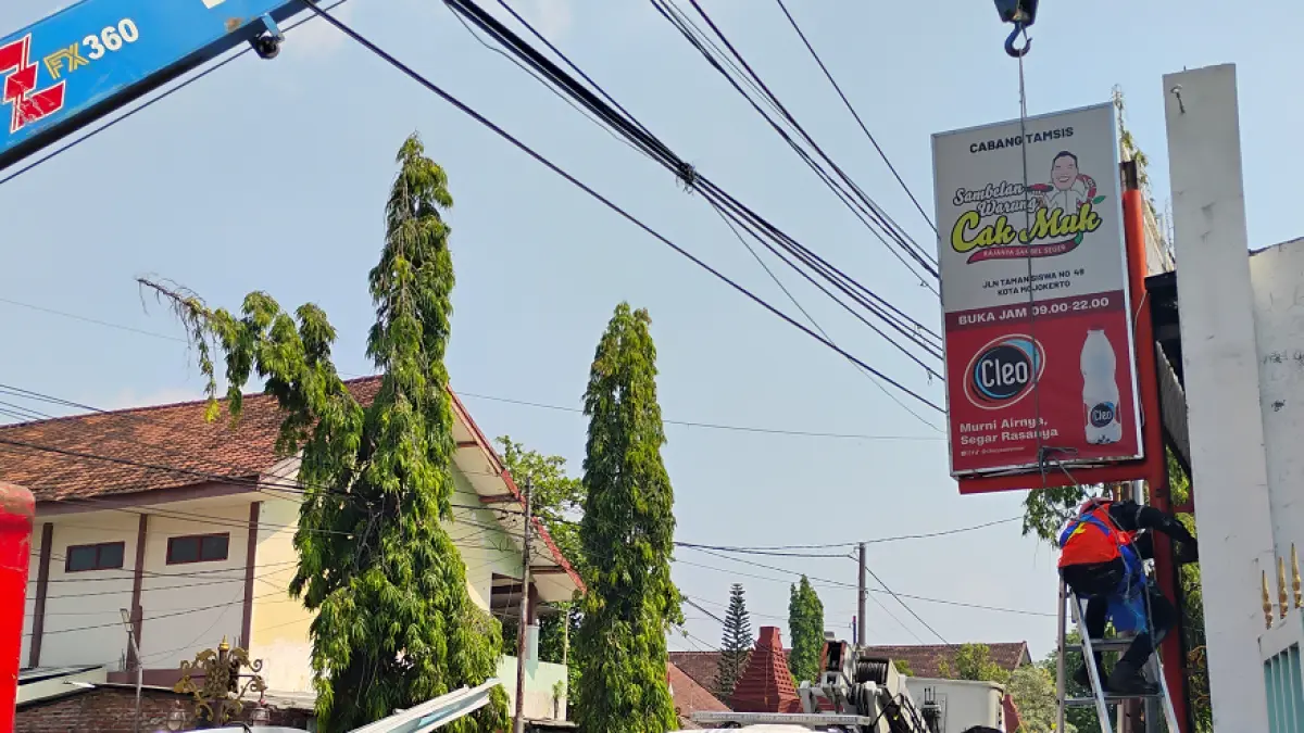 DIBONGKAR PAKSA: Petugas Satpol PP mencopot reklame permanen milik Warung Cak Muk di Jalan Taman Siswa, Kota Mojokerto, Senin (15/6). (Martda JPRM)