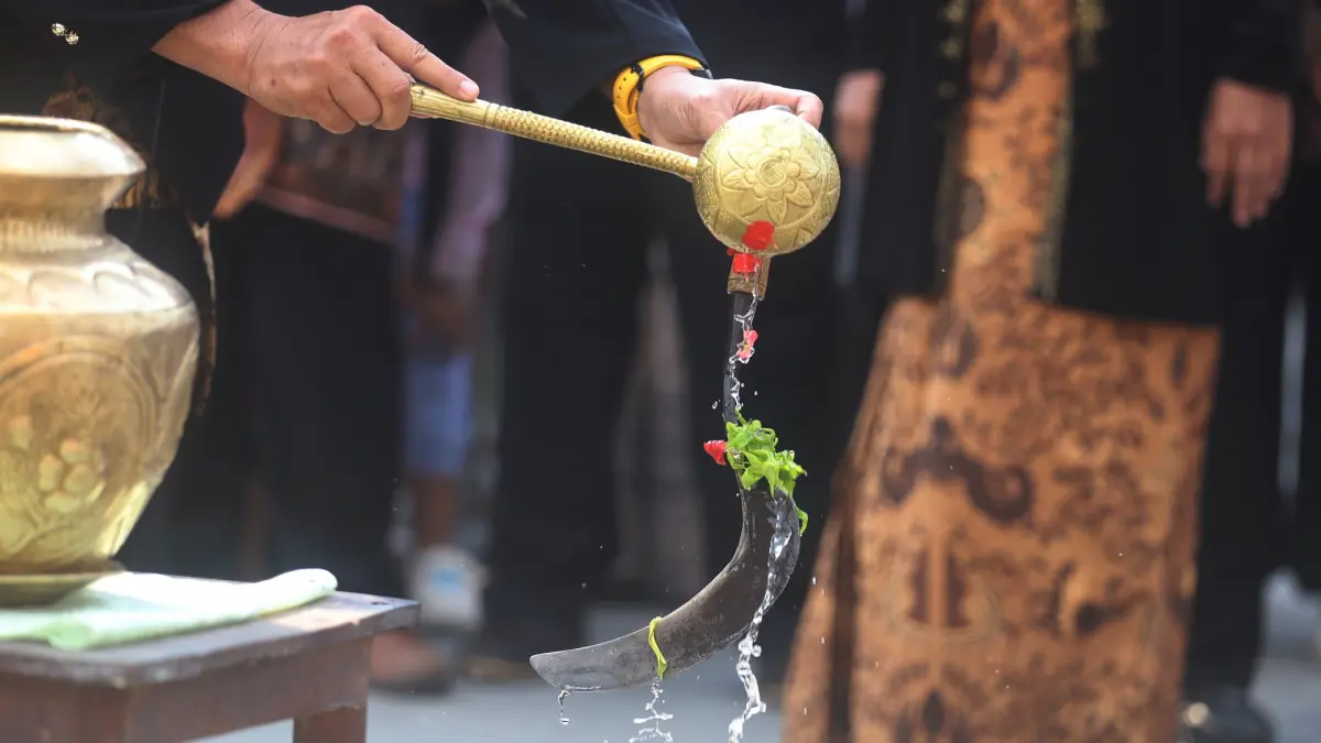 DISUCIKAN: Seorang pengampu adat mengguyurkan air suci ke sejumlah alat pertanian milik warga Desa Gembongan, Kecamatan Gedeg, Kabupaten Mojokerto, kemarin (27/6). Air suci diambil dari delapan sumber mata air. (Sofan JPRM)
