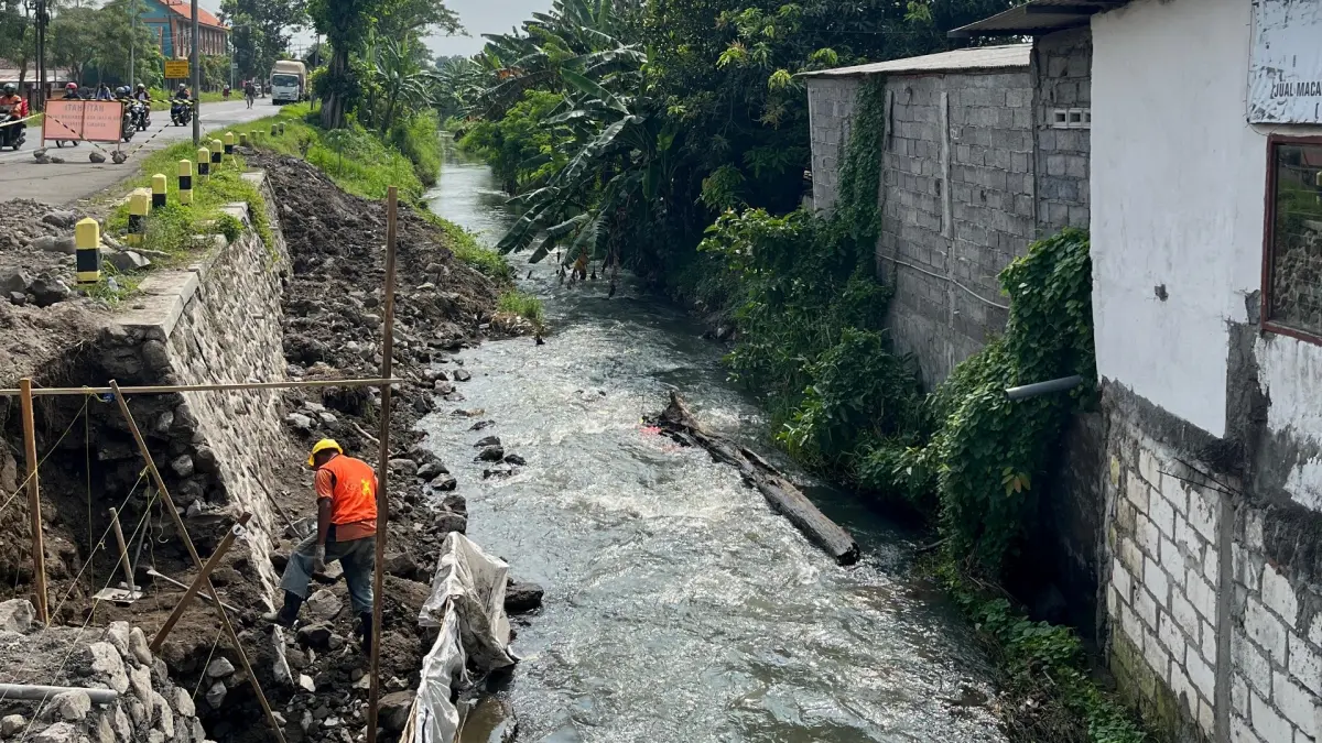 DIDANDANI: Petugas memperbaiki dinding penahan tanah di ruas Jalan Raya Jetis, Kecamatan Jetis, Kabupaten Mojokerto. (Martda JPRM)