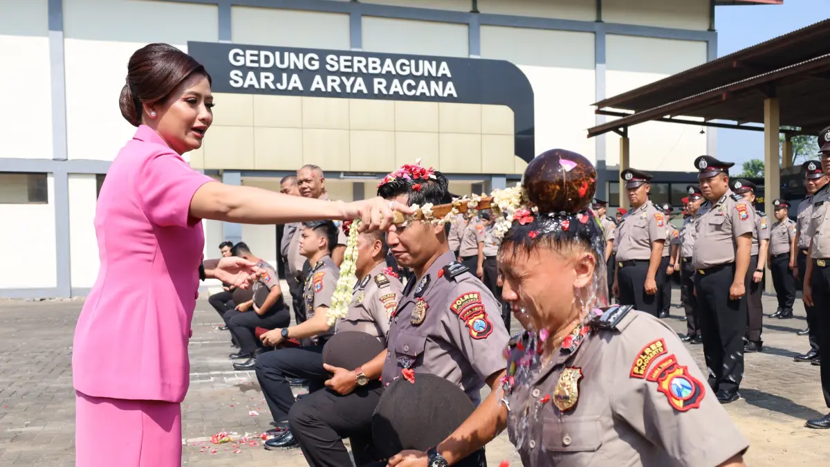 TRADISI: Ketua Bhayangkari Cabang Mojokerto Ny Diva Andi Yudha melakukan prosesi penyiraman air bunga kepada salah satu anggota Polres Mojokerto yang mendapat kenaikan pangkat, Rabu (1/7). (Rizal JPRM)