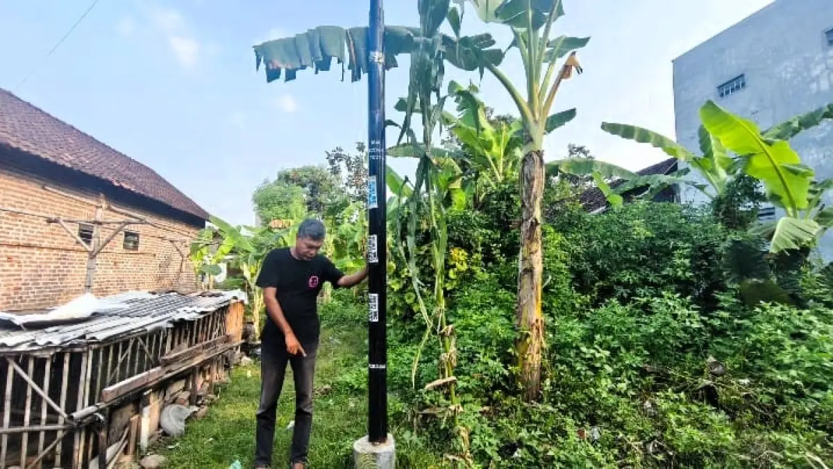 DISOAL: Nur Kholik menunjukkan tiang internet yang tiba-tiba terpasang di lahan miliknya di Lingkungan/Kelurahan Kedundung, Kota Mojokerto. (Martda JPRM)