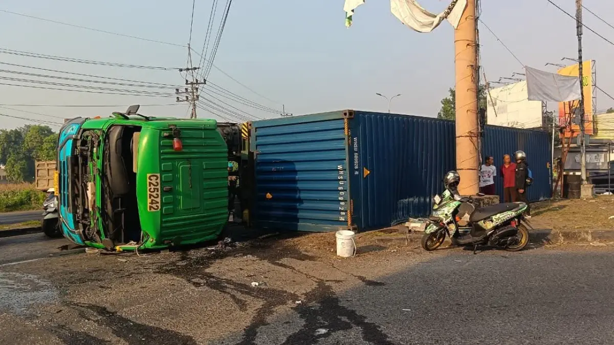 BERMUATAN TRIPLEKS: Kondisi bodi truk kontainer yang terguling di Jalan Raya Bypass, Desa Jampirogo, Kecamatan Sooko menutup lajur dari arah Jombang-Surabaya, Jumat (10/7). (Rizal JPRM)