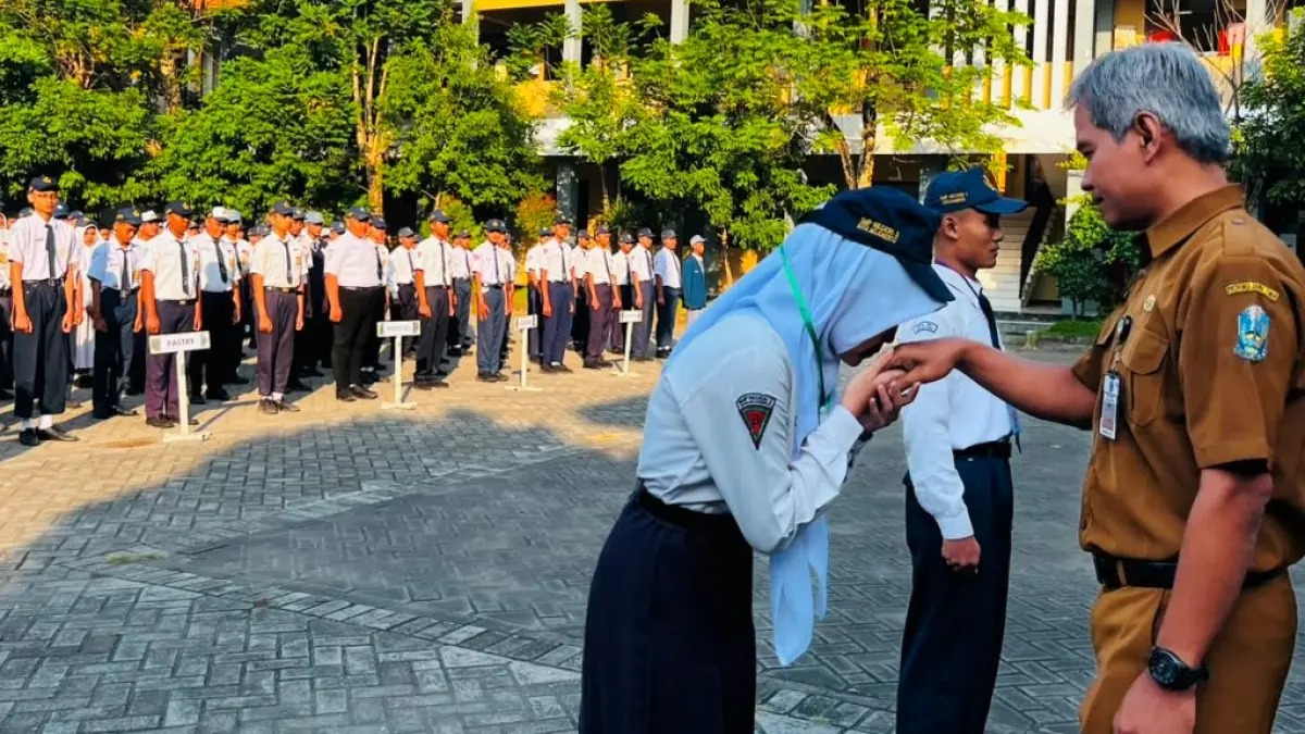 JADI KELUARGA: Kepala SMKN 2 Mojokerto Iswahyudi menyambut siswa baru setelah penyematan simbol pembukaan MPLS.