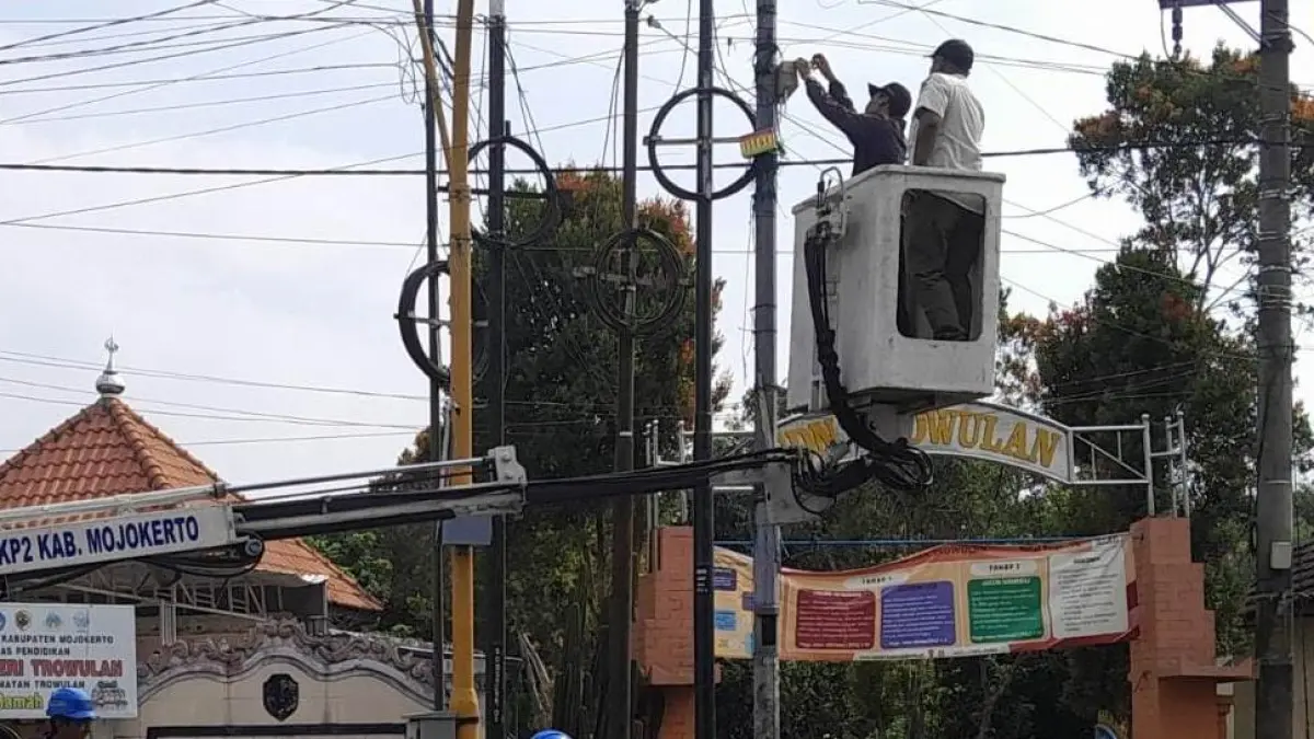 TINDAK TEGAS: Petugas gabungan satpol PP, diskominfo dan DPRKP2 Kabupaten Mojokerto melakukan penertiban kabel FO ilegal yang memanfaatkan PJU, Kamis (17/7). (Dori JPRM)