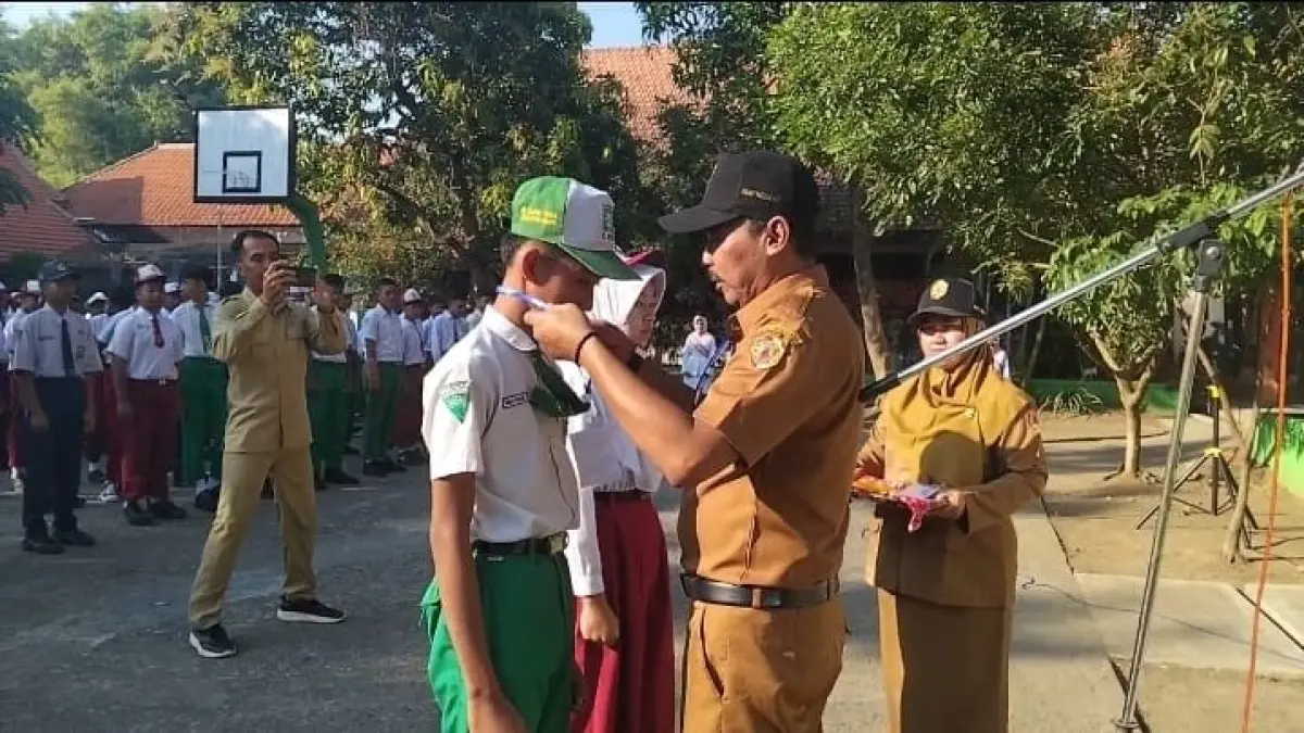 KELUARGA BARU: Kepala SMPN 2 Jatirejo Andhi Pristyandoyo Murti menyematkan tanda peserta MPLS kepada siswa baru, Senin (13/7).