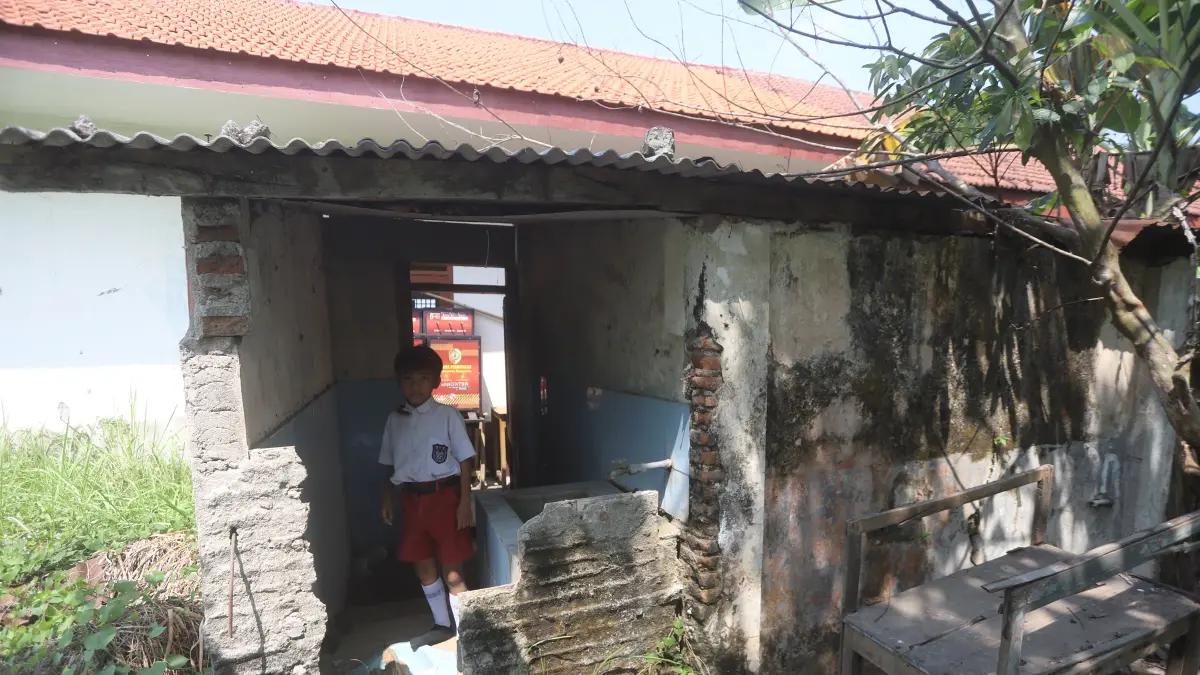 TANPA DINDING: Seorang siswa bermain di ruang toilet SDN Pandankrajan I, Kecamatan Kemlagi yang sebagian bangunan temboknya jebol dan tak terawat, kemarin (20/7). (Sofan JPRM)