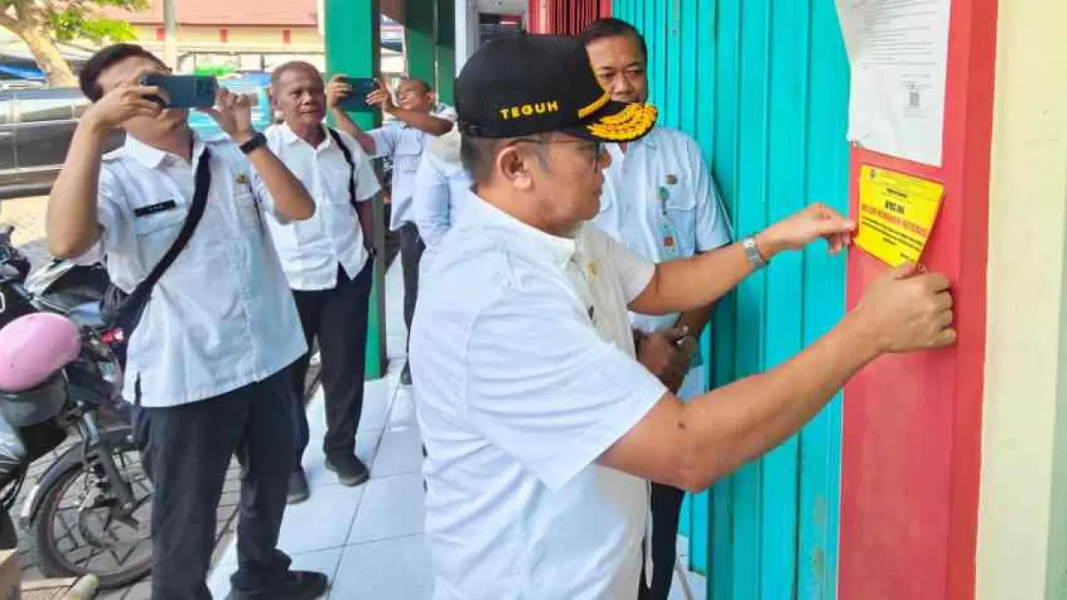 SANKSI SOSIAL: Sekdakab Mojokerto Teguh Gunarko menempel stiker himbauan kepada pemilik kios penunggak retribusi di lapak Pasar Kedungmaling, Kecamatan Sooko salah satunya sebagai sanksi sosial agar pedagang kian patuh, Rabu (22/7).