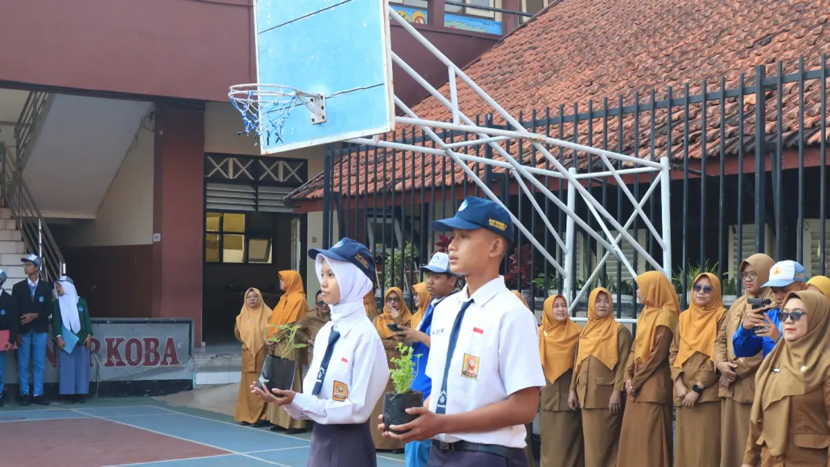 PEDULI LINGKUNGAN: Dua perwakilan peserta didik baru didampingi Kepala SMAN 3 Mojokerto membawa bibit tanaman saat upacara pembukaan MPLS di halaman sekolah, Senin (13/7). 