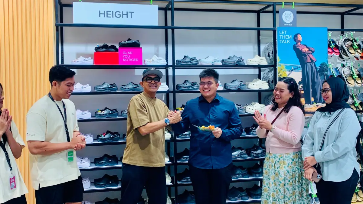SIMBOLIS: Direksi Sunrise Mall Mojokerto Kevin Utomo menerima potongan tumpeng dari perwakilan Crocs dalam acara opening, kemarin (23/7). (Dodik JPRM)