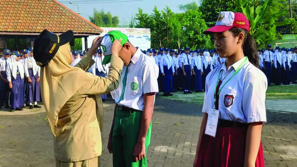 BERKARAKTER: Kepala SMPN 2 Jetis Niki Purwane Rahayu secara simbolis memakaikan topi kepada perwakilan peserta didik baru sebagai tanda dibukanya MPLS di lapangan SMPN 2 Jetis, Senin (13/7). (Indah JPRM)