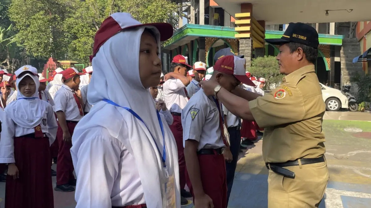 PENYAMBUTAN: Kepala SMPN 2 Trowulan Mokhamad Jalil menyematkan tanda peserta kepada siswa baru, Senin (13/7). (Indah JPRM)