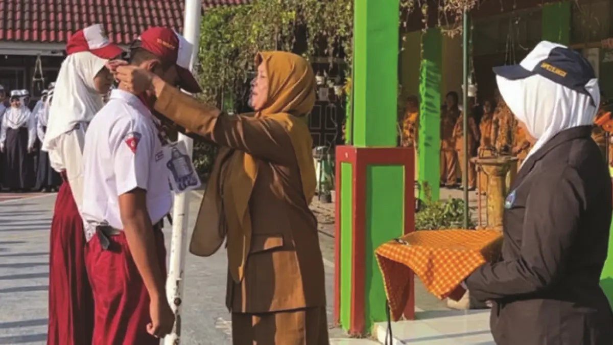 TAHUN AJARAN BARU: Kepala SMPN 2 Dlanggu Farida Hanim menyematkan tanda peserta MPLS Ramah 2026 secara simbolis kepada perwakilan siswa baru. (Adi JPRM)