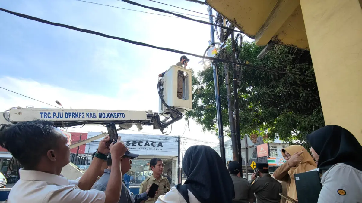 DITINDAK: Petugas gabungan melibatkan Satpol PP, Dinas PUPR, dan Komisi III DPRD Kabupaten Mojokerto menindak kebel FO gelap milik provider yang kedapatan dompleng tiang FO legal di wilayah Kecamatan Ngoro, kemarin (28/7). (Dori JPRM)