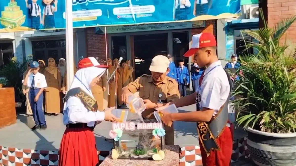 JAGA EKOSISTEM: Kepala SMPN 1 Pungging Sumantri secara simbolis melakukan pelepasan bibit ikan nila bersama perwakilan siswa baru.