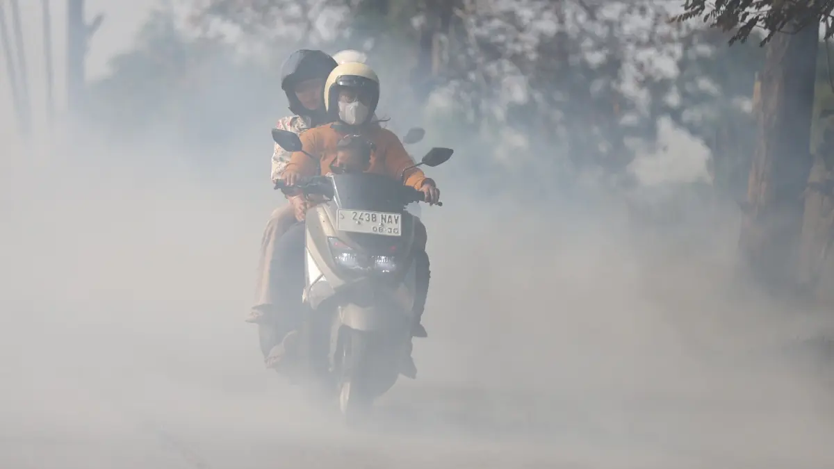 GANGGU PANDANGAN: Pengendara motor menerobos asap tebal akibat kebakaran lahan di Desa Suru, Kecamatan Dawarblandong, Kabupaten Mojokerto, kemarin (30/7). (Sofan JPRM)