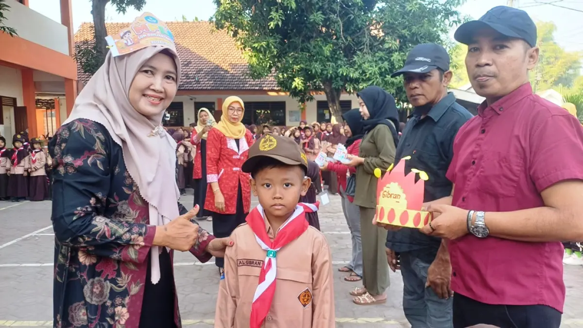 PENYAMBUTAN: Kepala Sekolah SDN Banjartanggul Laila Nur Alfiyah, S.Pd, memakaikan atribut sekolah sebagai tanda siswa siap menempuh pendidikan sekolah dasar selama 6 tahun.