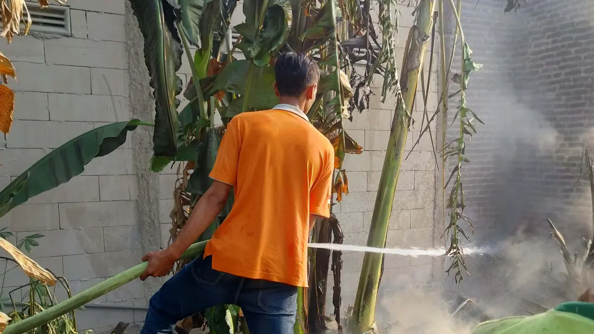 DIPADAMKAN:&nbsp;Petugas Damkar BPBD Kabupaten Mojokerto memadamkan api pada tumpukan limbah sampah yang menjalar ke rumah warga di Desa Peterongan, Kecamatan Bangsal, Kamis (6/8). (RIzal JPRM)