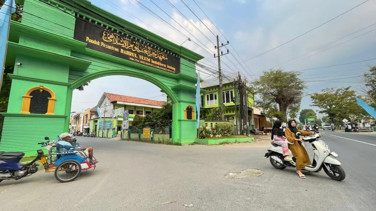 GERBANG UTAMA: Pengendara motor berboncengan keluar dari akses utama Lingkungan Pondok Pesantren Bahrul Ulum Tambakberas, Jombang.&nbsp;(Moch Chariris/JPRM)