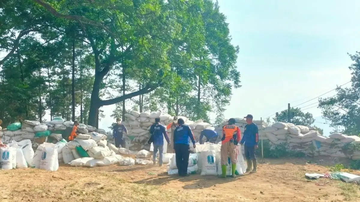 DIROMBAK: Relawan yang tergabung dalam FPRB, BPBD Kabupaten Mojokerto, dan UPT PJJ Dinas PU Bina Marga Jatim melakukan revitasliasi dinding sekam di rest area jalur Pacet-Cangar, Minggu (9/8). (Rizal JPRM)