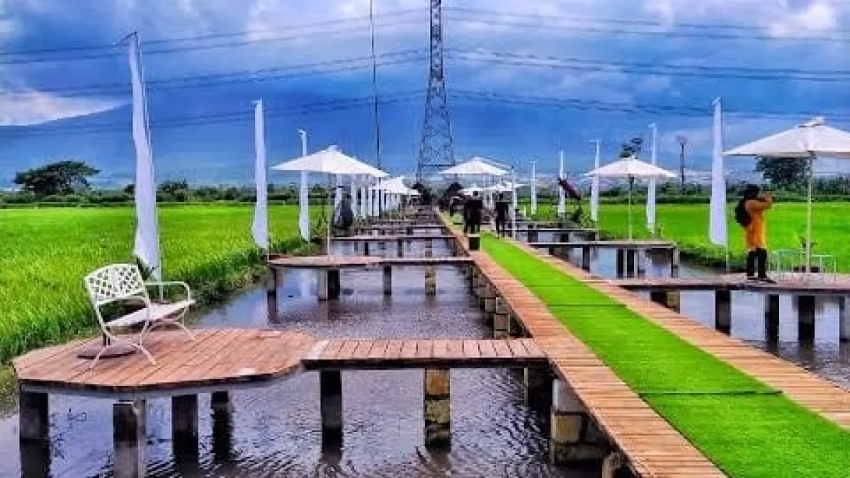 Suasana Gubuk Padi di tengah persawahan dengan jembatan kayu dan area bersantai yang menawarkan pemandangan hijau khas pedesaan Mojokerto.