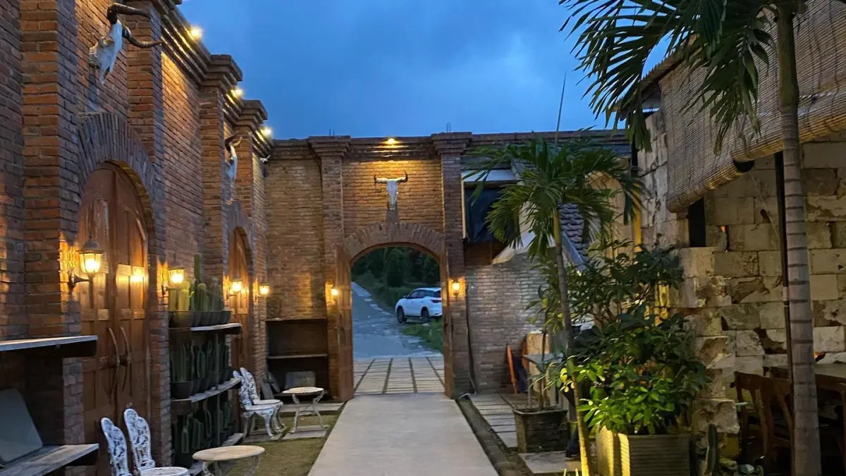 
Independent Cafe & Village Club di Trawas menawarkan suasana nongkrong dengan nuansa tradisional dan modern. Area cafe dihiasi bangunan bata, tanaman hijau, serta tempat duduk yang nyaman untuk bersantai.

