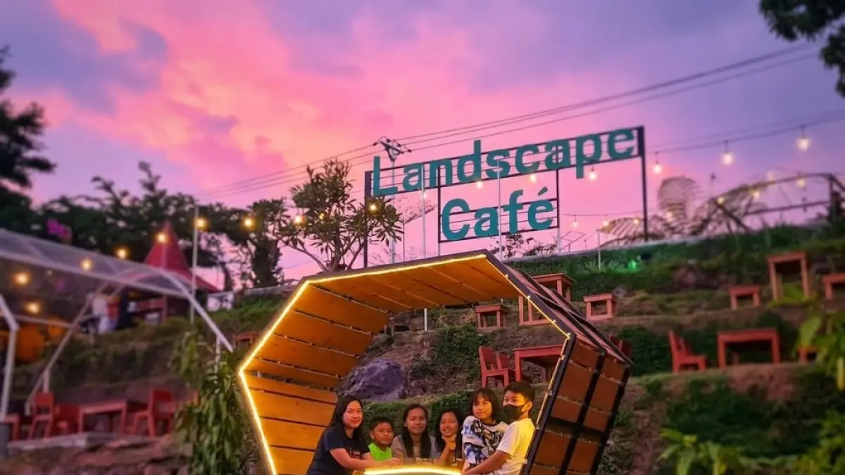 Sejumlah pengunjung bersantai di tempat duduk berbentuk heksagon yang dihiasi lampu dekoratif di Landscape Café, Mojokerto. Konsep ruang terbuka dengan latar langit senja ini menjadi salah satu daya tarik wisatawan untuk mengabadikan momen.