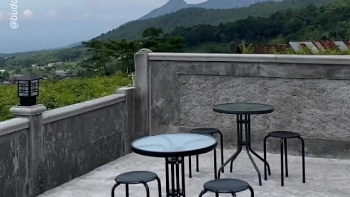 Area outdoor Nawasena Coffe Eatery Pacet menawarkan tempat duduk santai dengan panorama pegunungan sebagai latar.