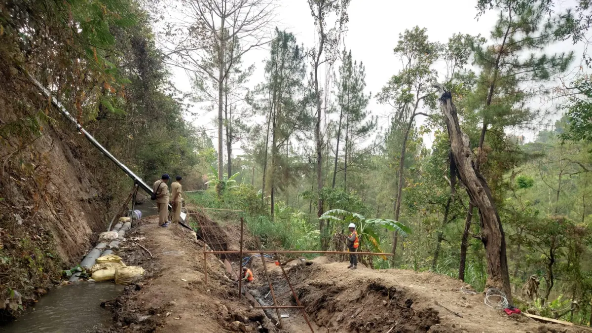 DIREHABILITASI: Petugas proyek dari Dinas PUPR Kabupaten Mojokerto mengerjakan perbaikan tebing tanggul irigasi di Desa Kuripansari, Kecamatan Pacet yang rusak akibat diterjang longsor tahun lalu. (Rizal JPRM)