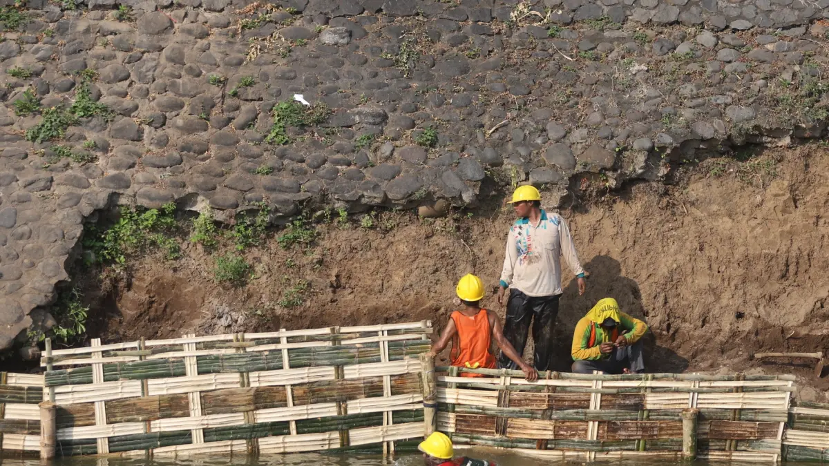 DIGARAP: Pekerja memperbaiki tanggul Sungai Brangkal yang ambrol di Gang Tanggul, Kelurahan Mentikan, Kecamatan Prajurit Kulon, Kota Mojokerto, Jumat (21/8). (Sofan Kurniawan/JPRM)