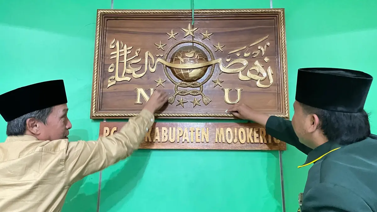 SAMBUT MUKTAMAR: Wakil Rais Syuriah PCNU Kabupaten Mojokerto KH Muhammad Ahdal Sidqulloh Amin (kiri) bersama kader membersihkan kaligrafi logo NU berbahan kayu, di kantor PCNU Kabupaten Mojokerto, Senin (24/8). (Chariris/JPRM)