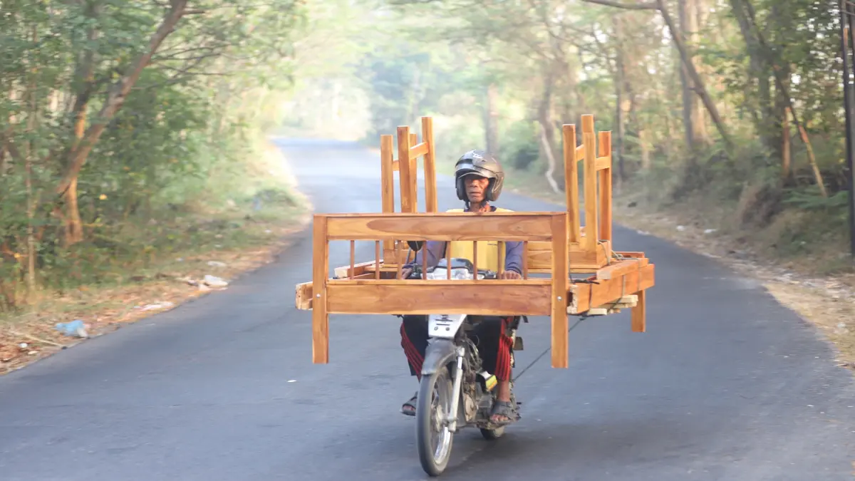 JAJAL PERUNTUNGAN: Warjo, seorang perajin dipan asal Desa Tawangsari, Kecamatan Mantup, Kabupaten Lamongan membawa mebel bikinannya dengan sepeda motor melintasi wilayah Jetis, Kabupaten Mojokerto, Rabu (19/8). (Sofan Kurniawan/JPRM)