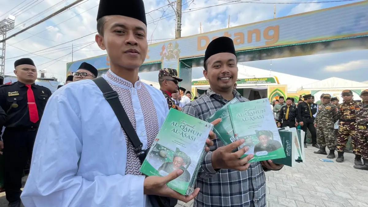 TENTANG SEJARAH: Dua pemuda menunjukkan dua buku yang dibagikan secara gratis kepada undangan dan muktamirin.