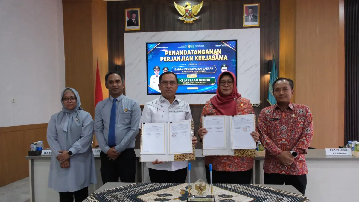 KOLABORASI: Kepala Kejari Kabupaten Mojokerto Fauzi bersama Kepala Bapenda Kabupaten Mojokerto Nurul Istiqomah&nbsp;menandatangani perjanjian kerja sama (PKS) penanganan hukum, di aula kantor Kejari Jalan RA Basuni, Kecamatan Sooko, Kamis (27/8). (Dori JPRM)