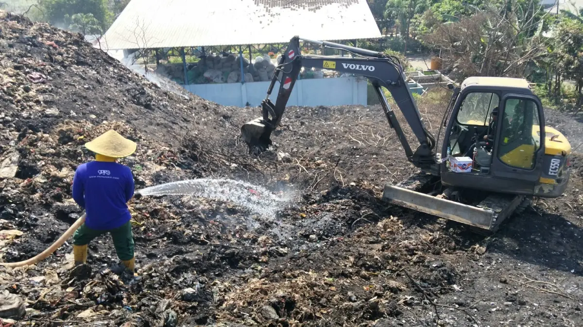 DIKENDALIKAN: Alat berat mengurai gunungan sampah di TPA Belahantengah, Kecamatan Mojosari, Kabupaten Mojokerto untuk dilakukan pembasahan pascakebakaran, Rabu (30/9). (Rizal/JPRM)