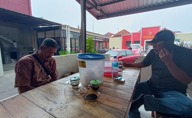 BERI PENJELASAN: Kades Madureso Suwarno (bertopi) dan ketua panitia PTSL Sujik saat di Mapolres Mojokerto Kota kemarin.