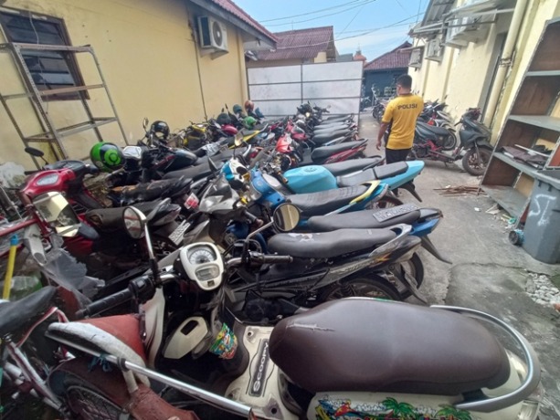 HASIL SITAAN: Petugas Satlantas Polres Mojokerto melintas di antara barang bukti kendaraan sejumlah kasus kemarin.