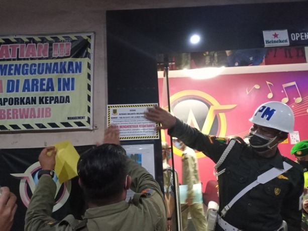 DIAWASI: Petugas Satpol PP Kota Mojokerto memasang stiker tanda penutupan selama Ramadan di tempat hiburan, Kamis (31/3) malam.