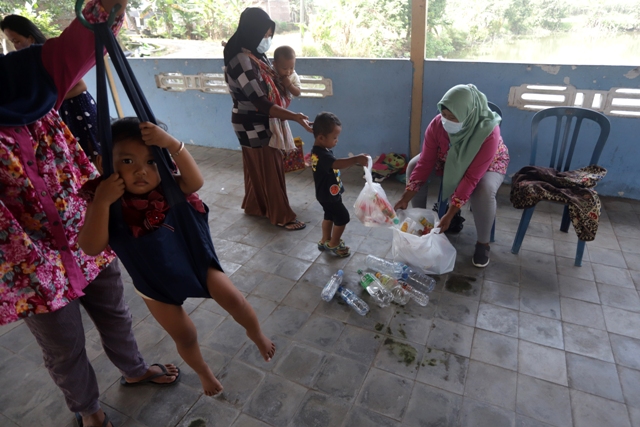 BERDAYA: Bidan desa menimbang sampah yang disetorkan oleh ibu-ibu posyandu sebelum memberikan imunisasi pada balita mereka di Ponkesdes Gunungsari, Kecamatan Dawarblandong.