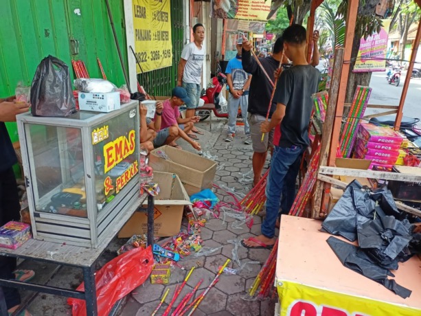 MEMBAHAYAKAN: Sejumlah karyawan kios kembang api milik Agus tengah menata sisa-sisa kembang api yang berhasil diamankan kemarin.