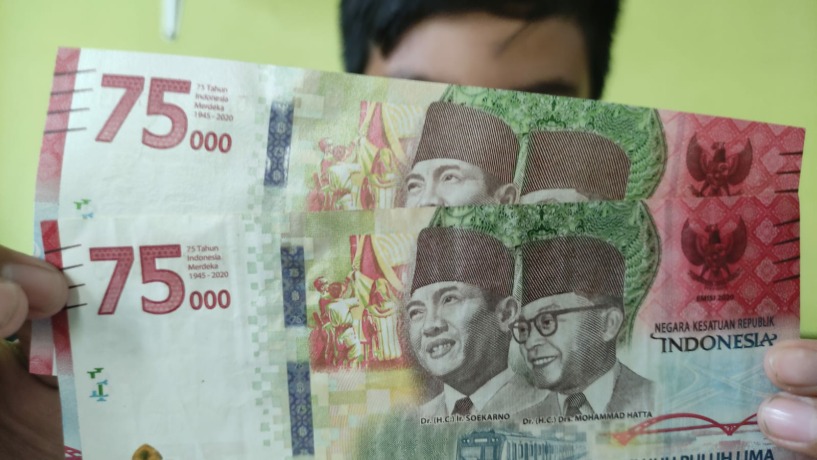 UANG BARU: Seorang warga menunjukkan uang pecahan Rp 75 ribu. (Moch Chariris/jawaposradsrmojokerto.id)